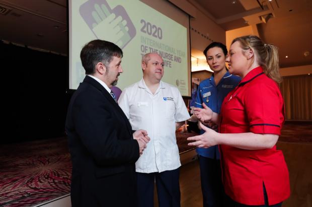 Health Minister Robin Swann is pictured with Student Nurse Craig Chambers, Staff Nurse Rebecca Stark (blue) and District Nursing Sister Ashleigh Pullins (red)